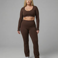 Woman wearing a fitted long sleeve crop top and high waist flare leggings activewear set styled with athletic sneakers.