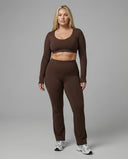 Woman wearing a fitted long sleeve crop top and high waist flare leggings activewear set styled with athletic sneakers.