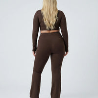 Woman wearing a fitted long sleeve crop top and high waist flare leggings activewear set styled with athletic sneakers.