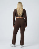 Woman wearing a fitted long sleeve crop top and high waist flare leggings activewear set styled with athletic sneakers.