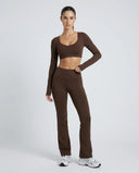 Woman wearing a fitted long sleeve crop top and high waist flare leggings activewear set styled with athletic sneakers.