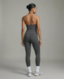 Model wearing a gray seamless halter sculpt leggings set with high waist fitted leggings and athletic sneakers.