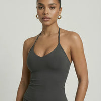 Model wearing a gray seamless halter sculpt leggings set with high waist fitted leggings and athletic sneakers.