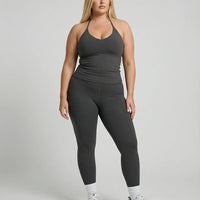 Model wearing a gray seamless halter sculpt leggings set with high waist fitted leggings and athletic sneakers.
