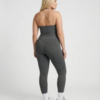 Model wearing a gray seamless halter sculpt leggings set with high waist fitted leggings and athletic sneakers.