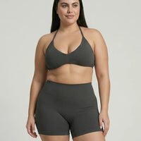 Model wearing a grey seamless sculpt gym set with high waist shorts and a supportive sports bra paired with athletic sneakers.