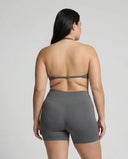 Model wearing a grey seamless sculpt gym set with high waist shorts and a supportive sports bra paired with athletic sneakers.