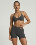 Model wearing a grey seamless sculpt gym set with high waist shorts and a supportive sports bra paired with athletic sneakers.