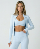 Women's 3-piece seen athletic set with flare pants, sports bra, and jacket, shown on a model in a fitness pose.