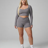 Seen women's activewear set with black sculpting biker shorts and long sleeve top, designed for workout and athleisure wear.