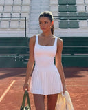Model wearing the SEEN Essential white tennis dress, front studio view showcasing the sculpting bodice and pleated skirt.
