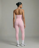 Model wearing a pink seamless halter sculpt leggings set with high waist fitted leggings and athletic sneakers.