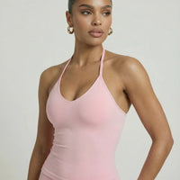 Model wearing a pink seamless halter sculpt leggings set with high waist fitted leggings and athletic sneakers.