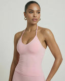 Model wearing a pink seamless halter sculpt leggings set with high waist fitted leggings and athletic sneakers.