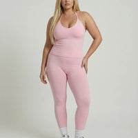 Model wearing a pink seamless halter sculpt leggings set with high waist fitted leggings and athletic sneakers.