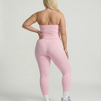 Model wearing a pink seamless halter sculpt leggings set with high waist fitted leggings and athletic sneakers.