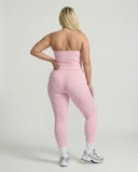 Model wearing a pink seamless halter sculpt leggings set with high waist fitted leggings and athletic sneakers.
