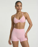 Model wearing a pink seamless sculpt gym set with high waist shorts and a supportive sports bra paired with athletic sneakers.