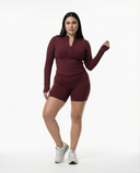 Plus size Woman wearing a fitted activewear set with high waist shorts and a zip-up jacket in a clean studio setting.