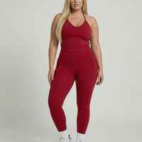 Model wearing a red seamless halter sculpt leggings set with high waist fitted leggings and athletic sneakers.
