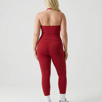 Model wearing a red seamless halter sculpt leggings set with high waist fitted leggings and athletic sneakers.