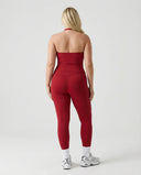 Model wearing a red seamless halter sculpt leggings set with high waist fitted leggings and athletic sneakers.