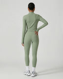 Woman wearing a seamless sculpting three piece activewear set with high waist leggings, sports bra, and fitted jacket paired with sneakers.