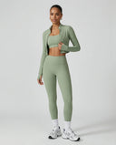 Woman wearing a seamless sculpting three piece activewear set with high waist leggings, sports bra, and fitted jacket paired with sneakers.
