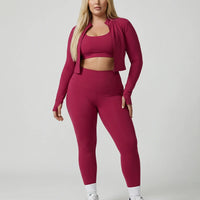 Woman wearing a seamless sculpting three piece activewear set with high waist leggings, sports bra, and fitted jacket paired with sneakers.