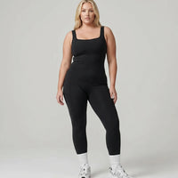 Model standing front-on in the black backless bodysuit in a white studio, showing the sculpting torso fit.