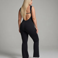 Model facing away in the black backless bodysuit, displaying the full open back design in studio lighting.