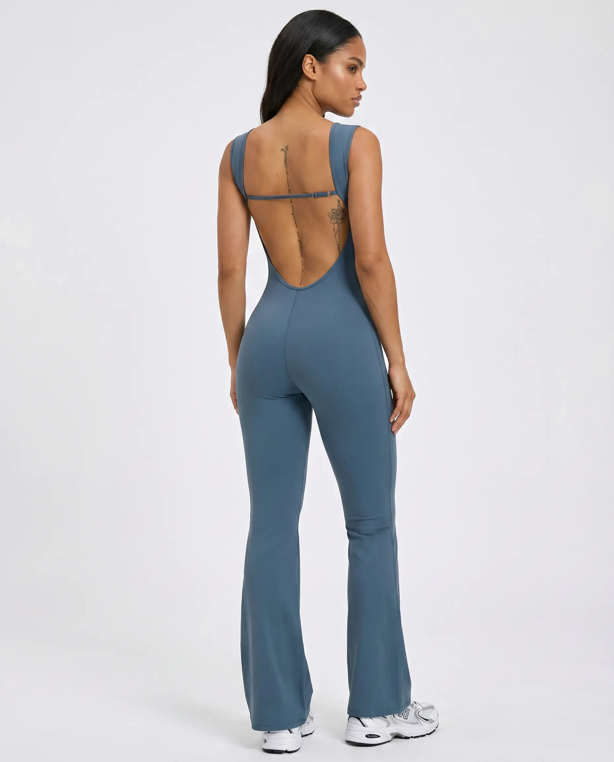 Back view of blue backless flare bodysuit on ghost mannequin highlighting open back cut and full-length flared legs.