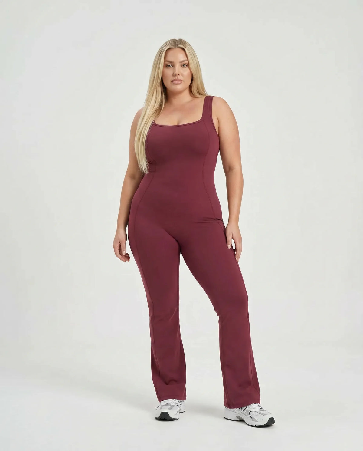 Female model wearing red flared backless bodysuit, front-facing in a studio setting.