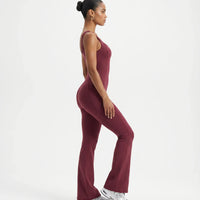 Plus size model wearing red backless bodysuit with flared legs, front view in studio.