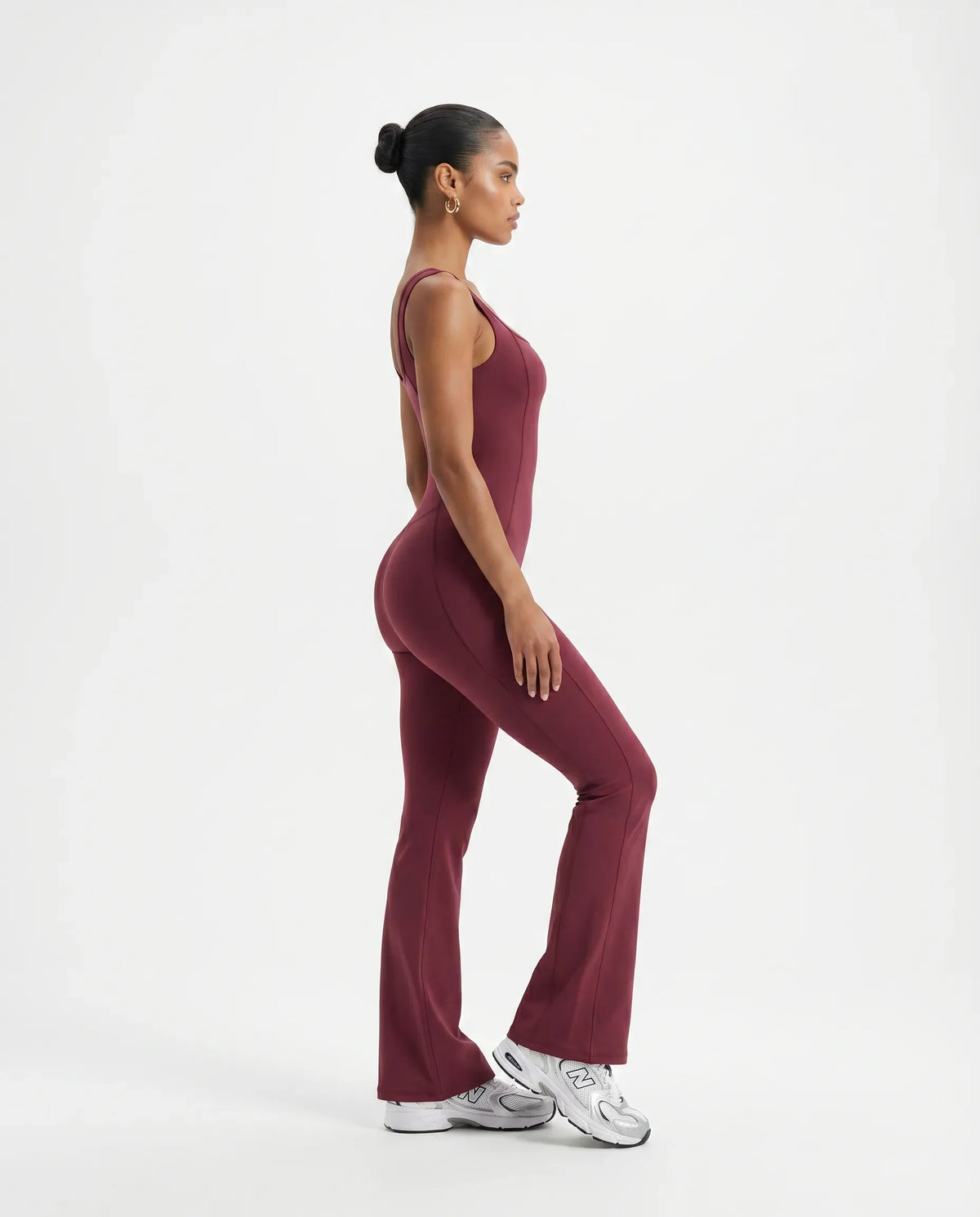 Plus size model wearing red backless bodysuit with flared legs, front view in studio.