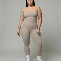 Model wearing gray backless bodysuit in front studio pose showing sculpting fit and sweetheart neckline.