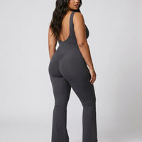 Model facing away from camera showing the deep open back of the ash bodysuit in a studio setting.
