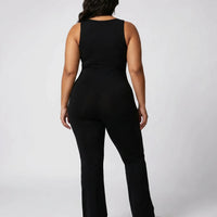 Model wearing black backless flare bodysuit from behind showing the open back and clean seam lines.