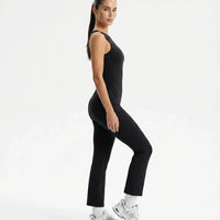 Plus size model wearing black backless flare bodysuit front view highlighting sculpting fit across the torso.