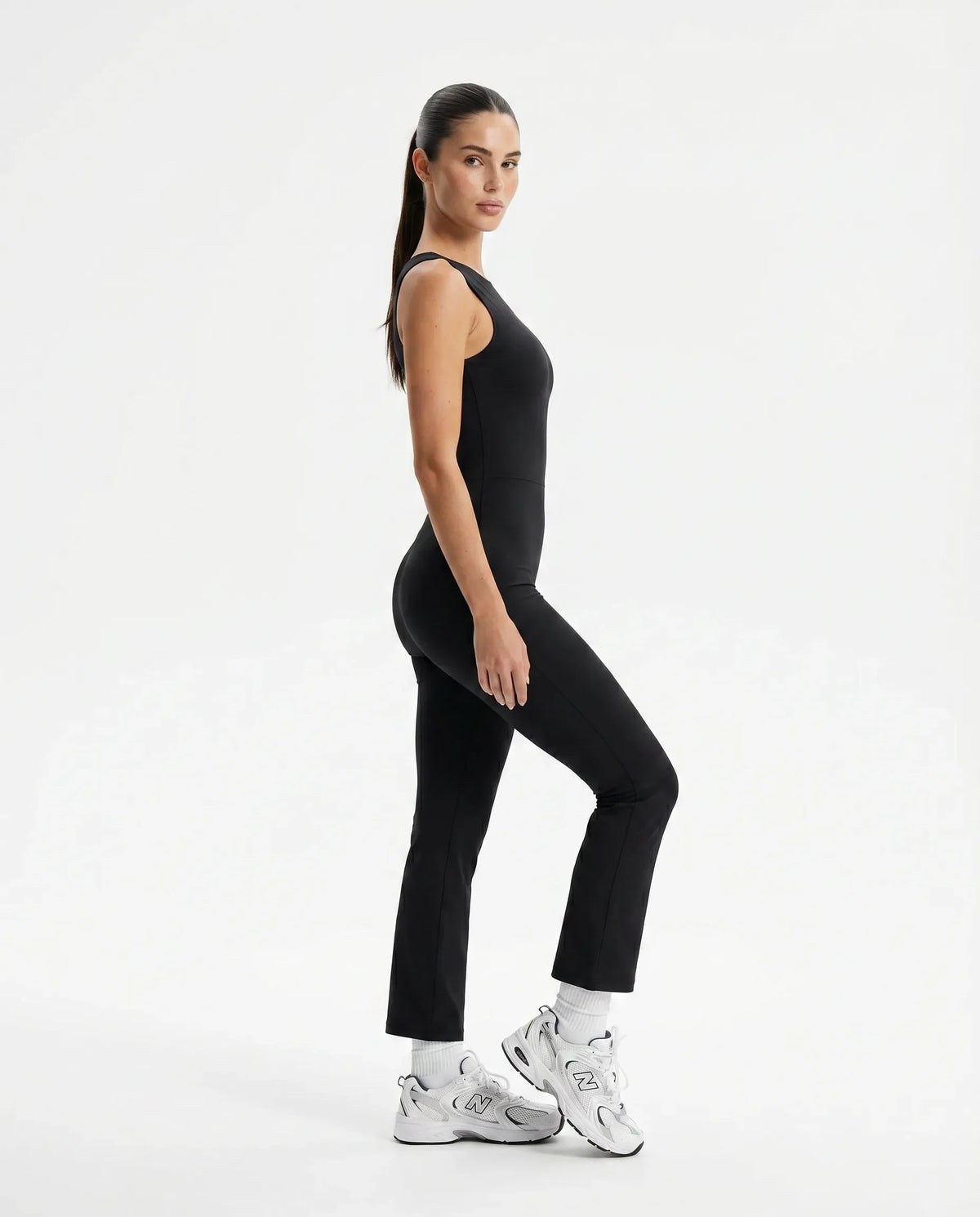 Plus size model wearing black backless flare bodysuit front view highlighting sculpting fit across the torso.