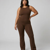 Model facing forward wearing brown backless flare bodysuit in a studio setting with a neutral background.