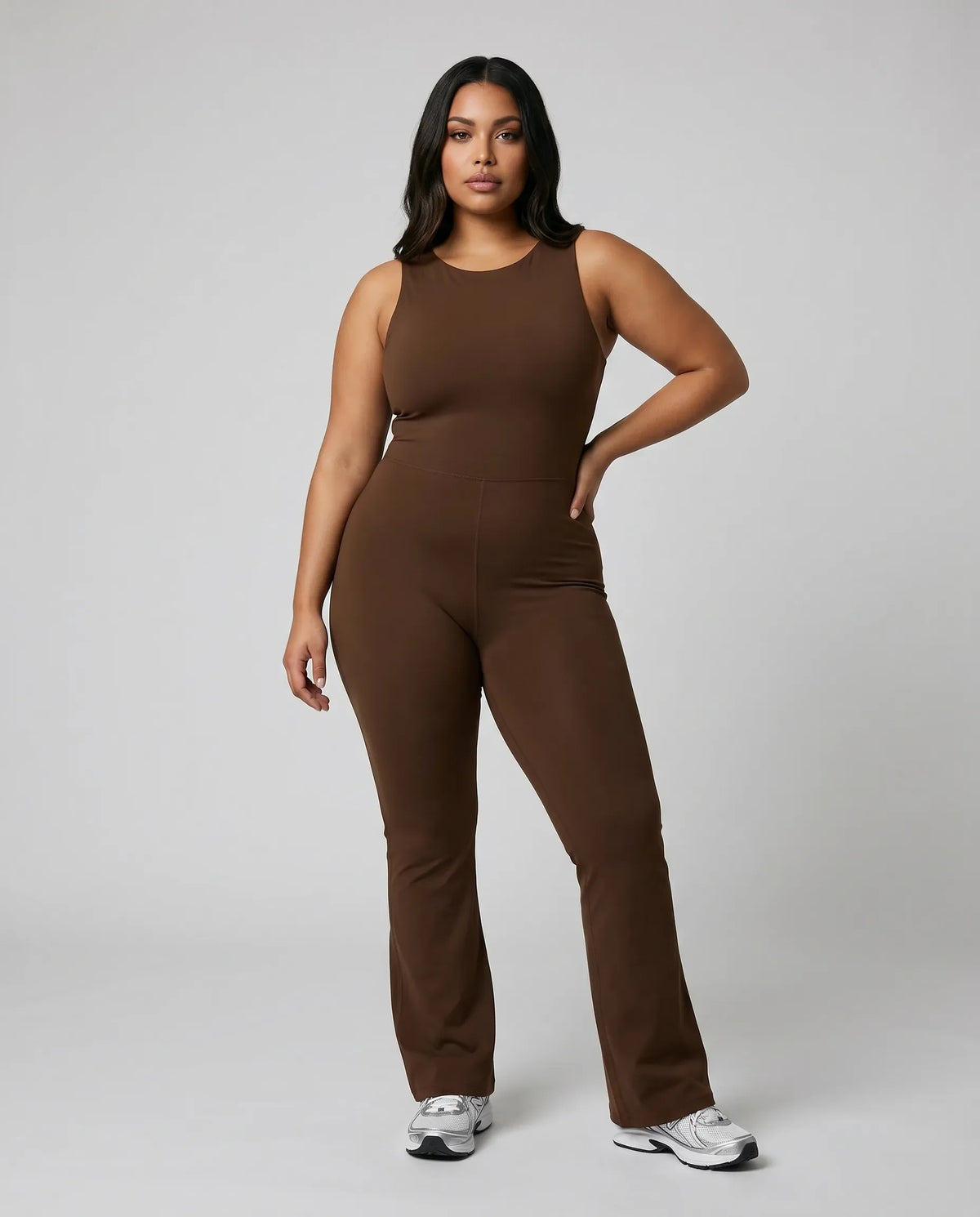 Model facing forward wearing brown backless flare bodysuit in a studio setting with a neutral background.
