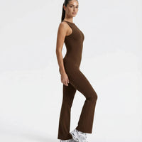 Plus size model facing forward wearing brown backless flare bodysuit, showing sculpting fit across the torso and flared legs.