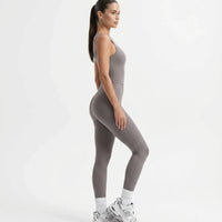 Plus size model front view wearing the purple backless bodysuit with flared legs in a studio setting.