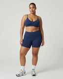 Model wearing the blue sculpting sports bra top, front view in a studio setting with neutral background.