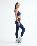 Woman wearing the blue sports bra top mid-workout in a bright lifestyle setting with natural light.