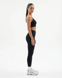 Plus size model facing front in a studio wearing a black compression bra top with a sculpting V-neckline.