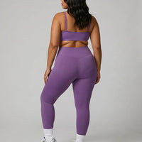 Model facing away in studio showing the back fit of the purple seamless bra top and high waist legging set.