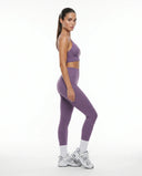 Plus size model back view in purple matching bra top and legging set highlighting smooth seamless construction across hips and thighs.