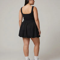 Model facing away showing the back of the black balloon mini dress in a studio setting.
